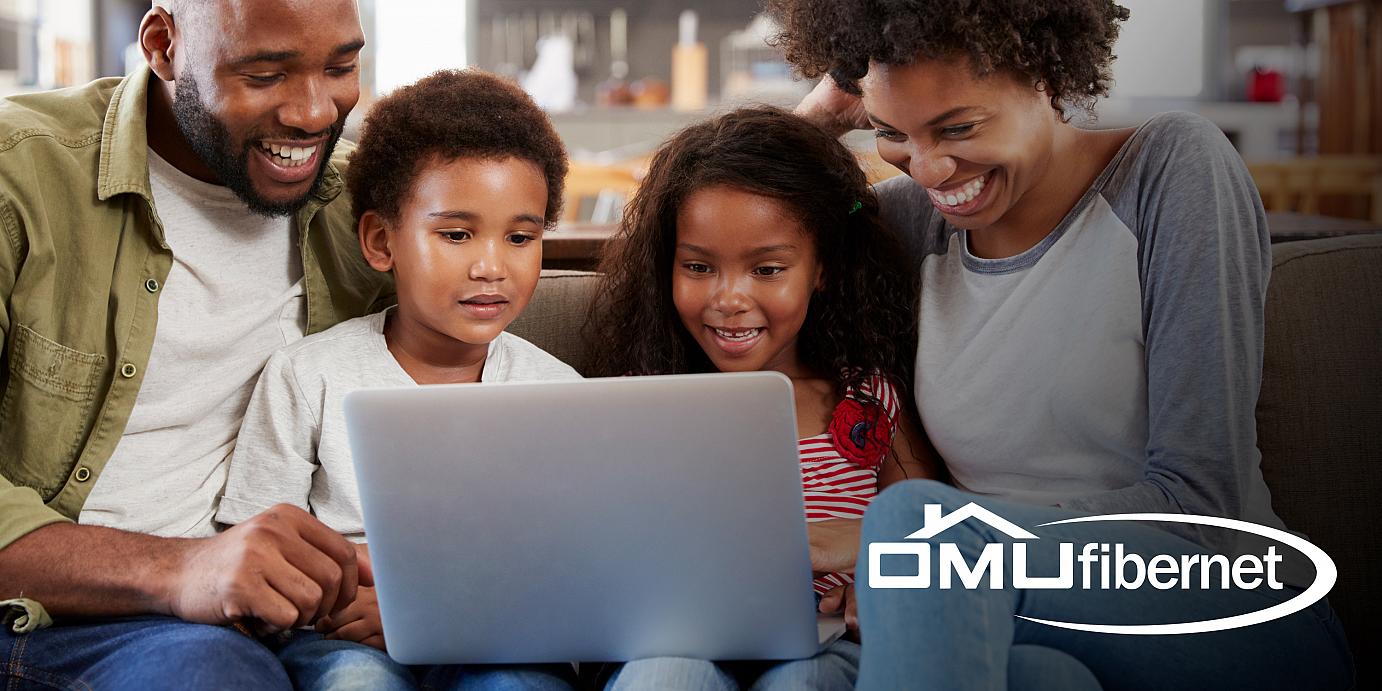 Smiling family huddled around laptop computer