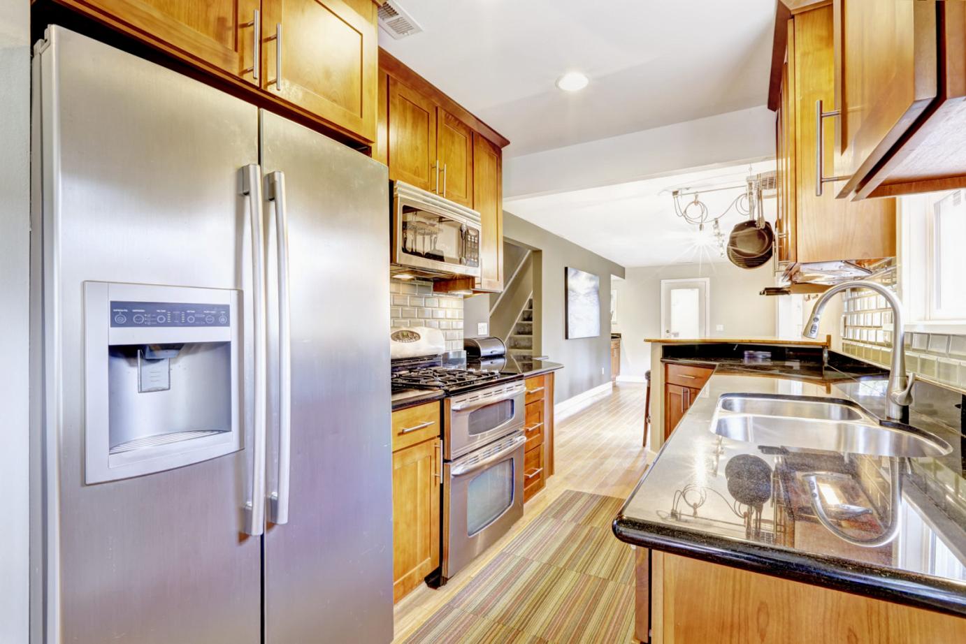 Narrow kitchen room interior with Cabinets and steel appliances.